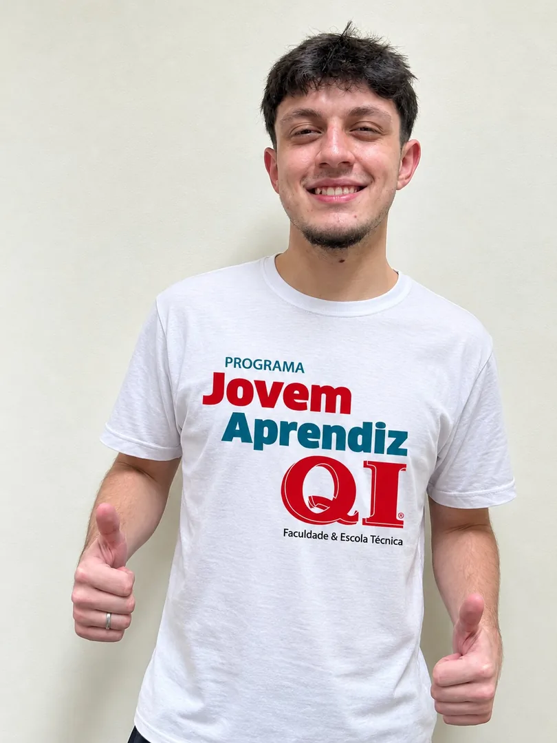 Daniel, Jovem Aprendiz da QI, de camiseta do Programa Jovem Aprendiz QI, sorrindo e mostrando os polegares para cima