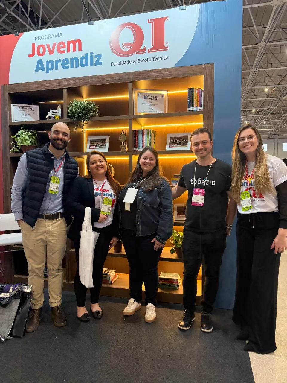 Grupo sorrindo diante do estande do Jovem Aprendiz QI