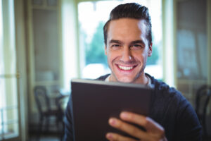 Homem sorridente utilizando um tablet, refletindo uma marca pessoal de confiança e profissionalismo no ambiente de trabalho.